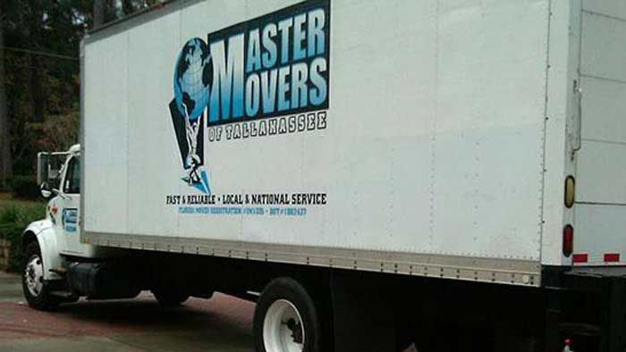 Moving truck with "Master Movers" logo parked outdoors.